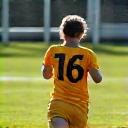 Criança a correr rapidamente em campo de futebol, representando aspectos físicos.